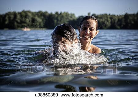 Stock Photo - Couple splashing in water, smiling, Berlin, Germany. Fotosearch