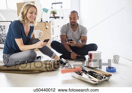 Stock Image - Couple taking break during apartment renovation. Fotosearch