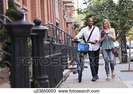Stock Image - Couple walking with bicycle and exercising mat. Fotosearch
