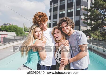 Stock Image - Couples hugging, pool in background. Fotosearch