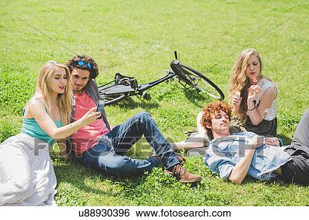 Stock Photograph - Couples relaxing in park. Fotosearch
