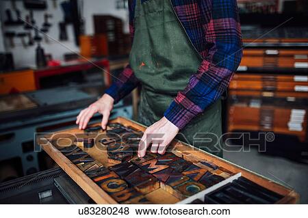 Crop of young craftsman looking through tray of wooden letterpress letters in print workshop View Large Photo Image Stock Photo - Crop of young craftsman looking through tray of wooden letterpress letters in print workshop. Fotosearch