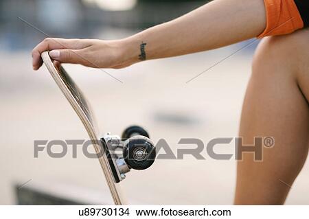 Picture - Cropped shot of female skateboarder holding skateboard. Fotosearch