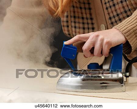 Stock Image - Cropped shot of young female designer steam ironing fabric. Fotosearch