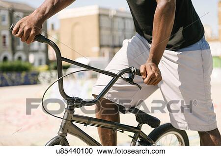 Stock Image - Cropped shot of young man on BMX bicycle in skatepark. Fotosearch