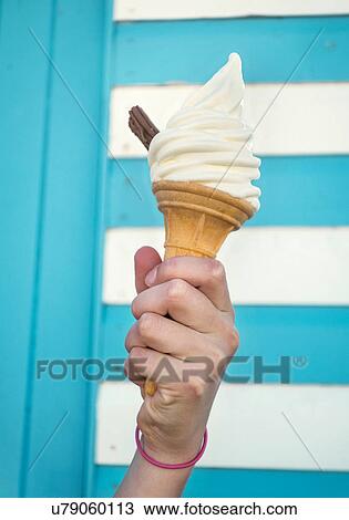 Stock Image - Cropped view girl's hand holding ice cream. Fotosearch