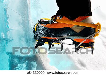 Stock Photo - Cropped view of ice climbers feet wearing crampons. Fotosearch