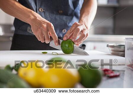 Stock Photo - Cropped view of man slicing limes. Fotosearch