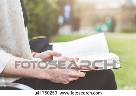 Stock Image - Cropped view of woman holding open book, London, UK. Fotosearch