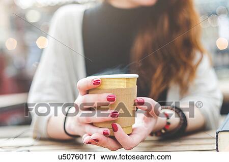Stock Image - Cropped view of woman holding disposable cup, London, UK. Fotosearch