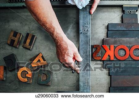 Stock Image - Detail of hand using letterpress machine in book arts workshop, overhead view. Fotosearch