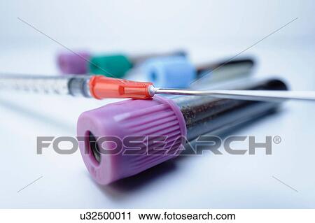 Stock Image - Disposable medical syringe and vials containing blood samples. Fotosearch