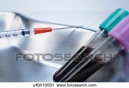 Stock Image - Disposable medical syringe and vials containing blood samples in kidney dish. Fotosearch