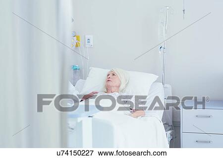 Stock Photo - Doctor talking to worried senior female patient in hospital bed. Fotosearch