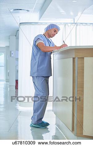 Doctor writing up medical notes at hospital nurses station View Large Photo Image Stock Photo - Doctor writing up medical notes at hospital nurses station. Fotosearch