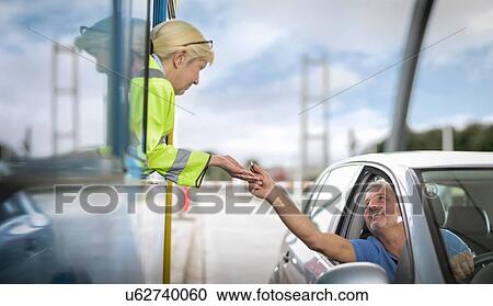 Stock Image - Driver in car paying toll booth at bridge. Fotosearch