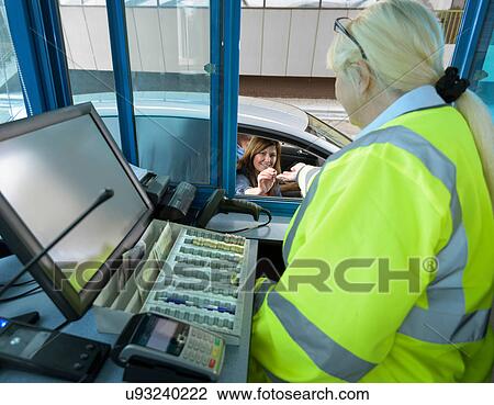 Stock Image - Driver in car paying toll booth at bridge. Fotosearch