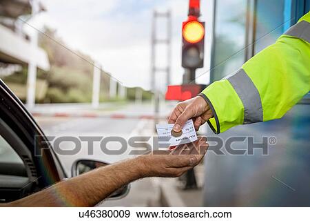 Stock Photo - Driver in car paying toll booth at bridge, close up. Fotosearch