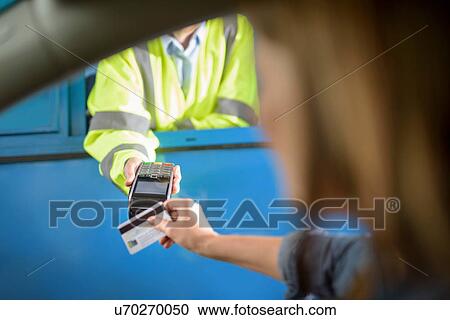 Stock Image - Driver in car paying toll booth using contactless card payment technology, close up. Fotosearch