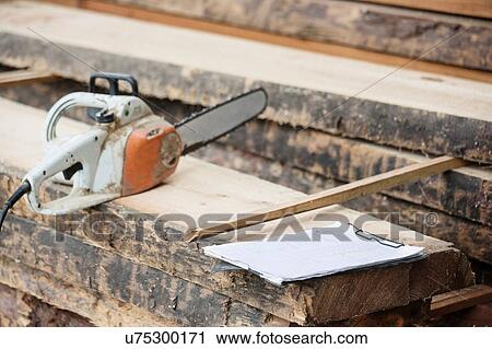 Stock Image - Electric saw on wooden plank. Fotosearch