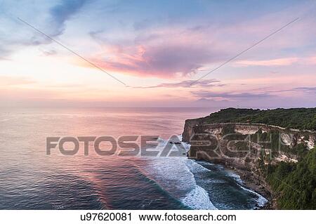 Stock Image - Elevated view of cliffs and sea at sunset, Uluwatu, Bali, Indonesia. Fotosearch