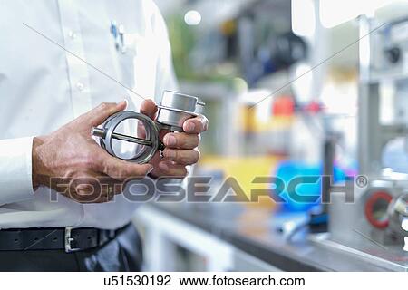 Stock Image - Engineer holding 3D printed parts in factory, close up. Fotosearch