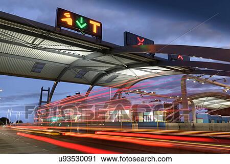 Stock Image - Evening view of cars passing through toll booth at bridge. Fotosearch