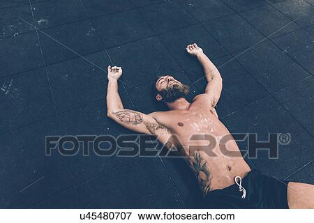 Exhausted male cross trainer lying on gym floor View Large Photo Image Stock Photo - Exhausted male cross trainer lying on gym floor. Fotosearch
