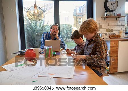 Exhausted man at dining table with laptop whilst son colouring View Large Photo Image Stock Photography - Exhausted man at dining table with laptop whilst son colouring. Fotosearch