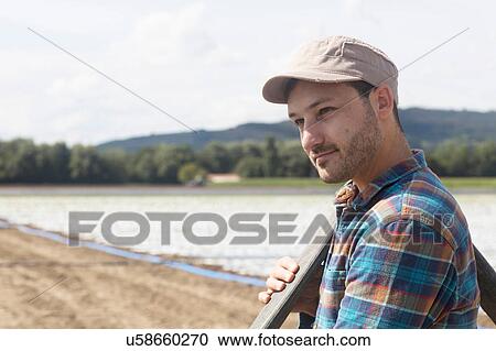 Farmer in field carrying pipe on shoulder View Large Photo Image Stock Image - Farmer in field carrying pipe on shoulder. Fotosearch
