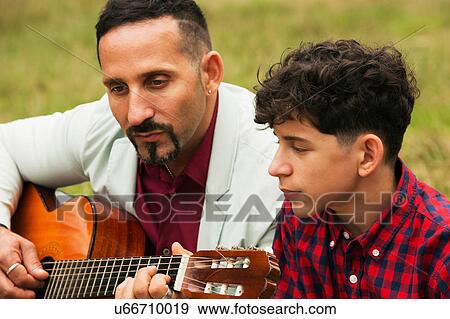 Father and son outdoors, father playing guitar View Large Photo Image Stock Photo - Father and son outdoors, father playing guitar. Fotosearch