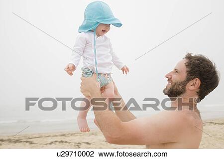 Father lifting baby son (6-11 months) on beach View Large Photo Image Stock Image - Father lifting baby son (6-11 months) on beach. Fotosearch