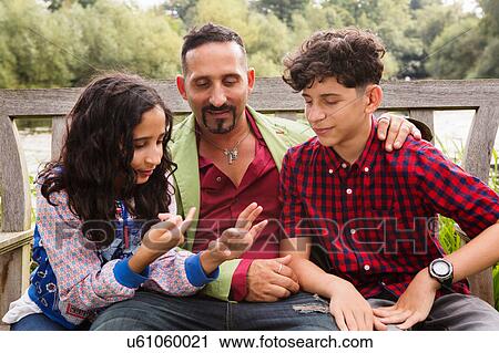 Father sitting on bench with son and daughter, daughter counting on fingers View Large Photo Image Stock Image - Father sitting on bench with son and daughter, daughter counting on fingers. Fotosearch