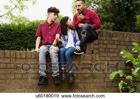 Father sitting on wall with son and daughter View Large Photo Image Stock Photo - Father sitting on wall with son and daughter. Fotosearch