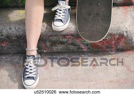 Stock Photograph - Feet of female skateboarder with skateboard on step. Fotosearch
