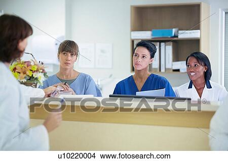 Female doctor having discussion with nurses at nurses station in hospital View Large Photo Image Picture - Female doctor having discussion with nurses at nurses station in hospital. Fotosearch