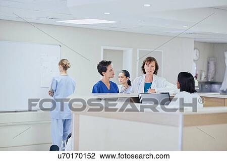 Female doctor having discussion with nurses at nurses station in hospital View Large Photo Image Stock Image - Female doctor having discussion with nurses at nurses station in hospital. Fotosearch