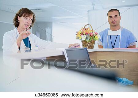 Female doctor talking at nurses station in hospital View Large Photo Image Stock Photography - Female doctor talking at nurses station in hospital. Fotosearch