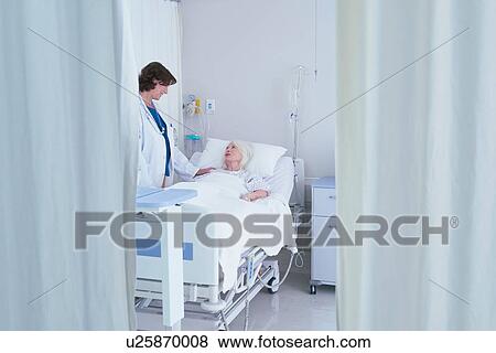 Female doctor talking to senior female patient in hospital bed View Large Photo Image Stock Photo - Female doctor talking to senior female patient in hospital bed. Fotosearch
