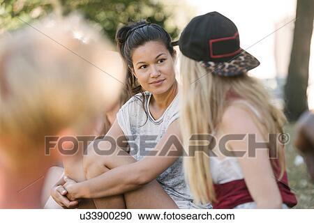 Stock Image - Female friends chatting in park. Fotosearch
