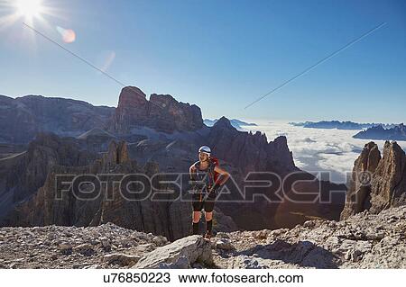 Stock Image - Female hiker arriving on Paternkofel mountain peak, Dolomites, Sexten, South Tyrol, Italy. Fotosearch