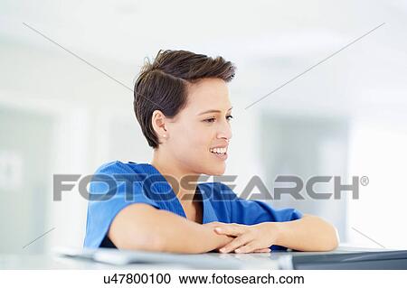 Stock Image - Female nurse leaning on nurses station in hospital. Fotosearch