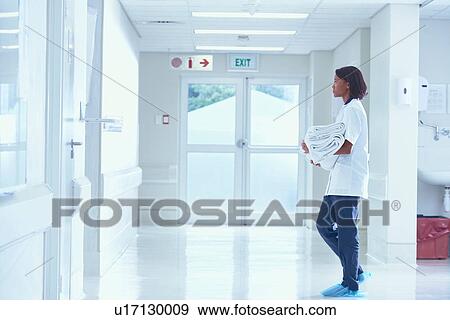 Stock Photo - Female orderly carrying towels on hospital corridor. Fotosearch