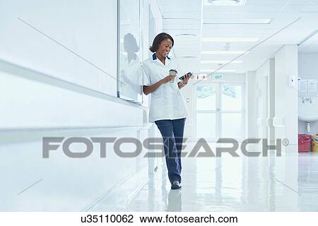 Female orderly reading smartphone texts on hospital corridor View Large Photo Image Stock Image - Female orderly reading smartphone texts on hospital corridor. Fotosearch