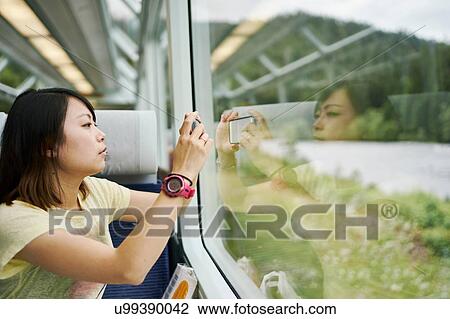 Female tourist photographing through passenger train window, Chur, Switzerland View Large Photo Image Stock Image - Female tourist photographing through passenger train window, Chur, Switzerland. Fotosearch