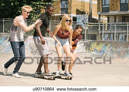 Picture - For adult friends learning to skateboard in skatepark. Fotosearch