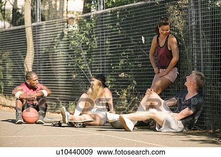 Four adult skateboarder friends sitting chatting on basketball court View Large Photo Image Stock Photo - Four adult skateboarder friends sitting chatting on basketball court. Fotosearch