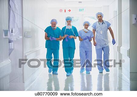 Four medical staff wearing scrubs walking in hospital corridor View Large Photo Image Stock Photo - Four medical staff wearing scrubs walking in hospital corridor. Fotosearch