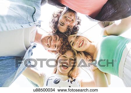 Picture - Friends doing team huddle in park. Fotosearch