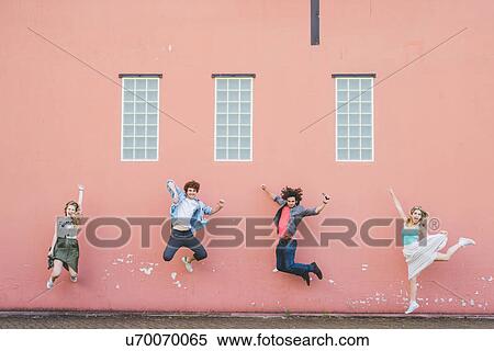 Friends jumping against pink wall background View Large Photo Image Stock Photography - Friends jumping against pink wall background. Fotosearch
